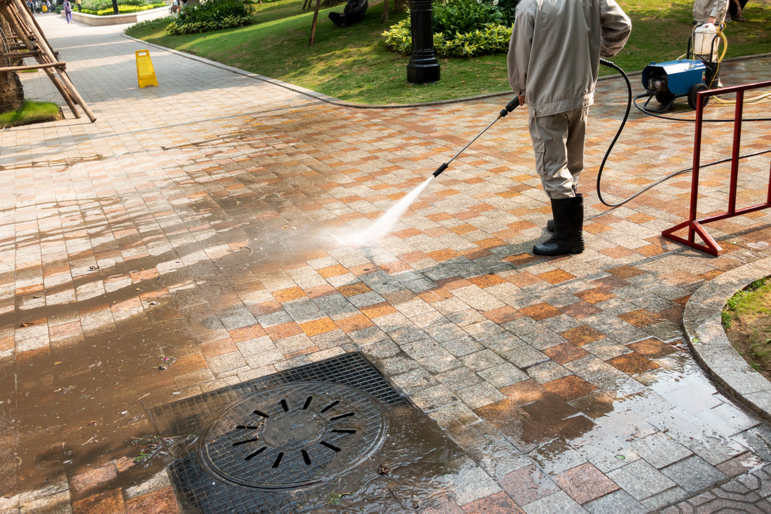 Block paving being jet washed and cleaned by worker