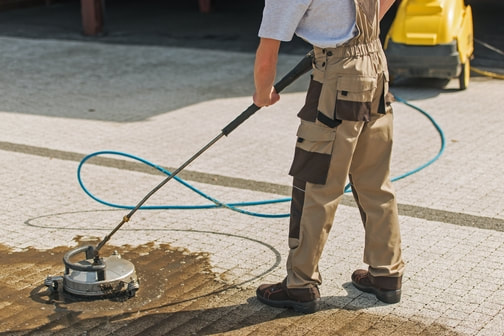 Man cleaning block paved driveway with rotary jet cleaning device