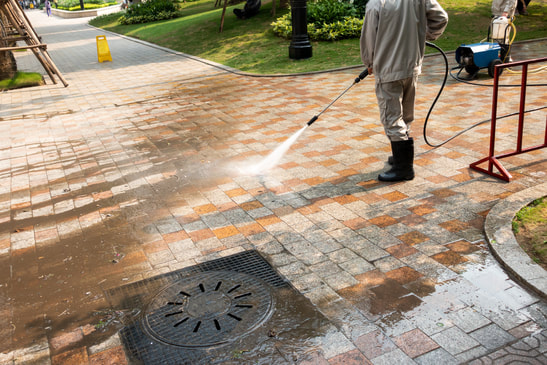 Man jet washing block paved driveway with standard lance