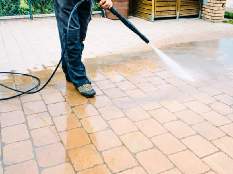 Worker jet washing brick patio pavers